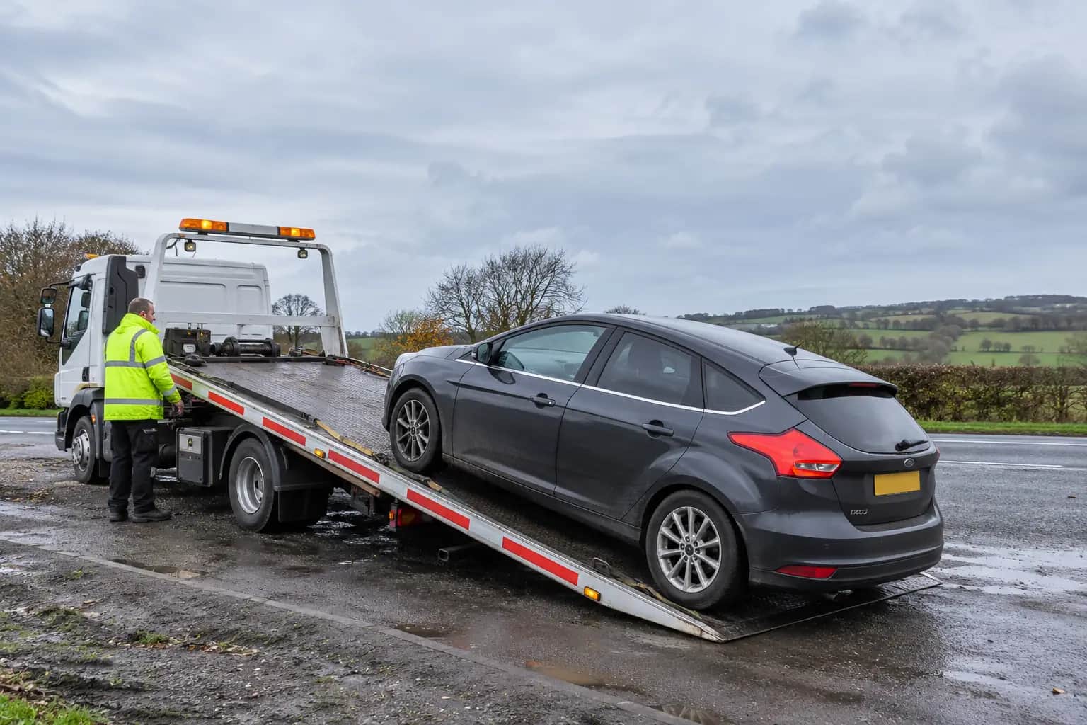 Car being loaded onto a flatbed recovery truck on a rural road near the A167