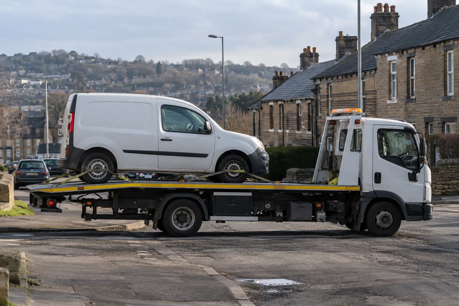 Van loaded onto a flatbed recovery truck on a residential street